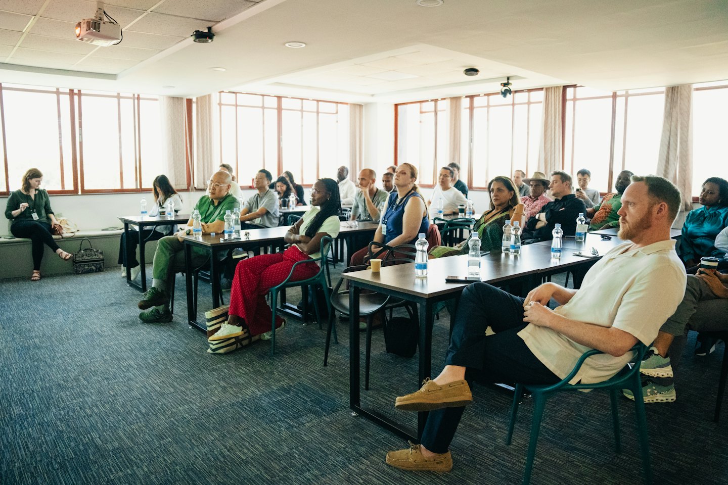 Adults attend a professional conference, taking notes at tables.